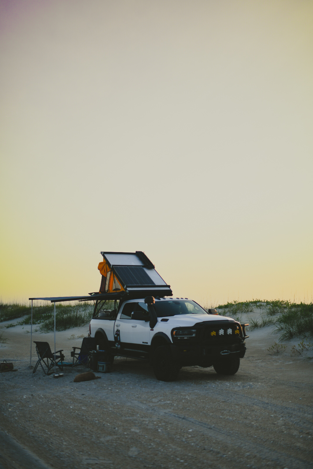 Truck with a rooftop tent camped on the beach at sunset