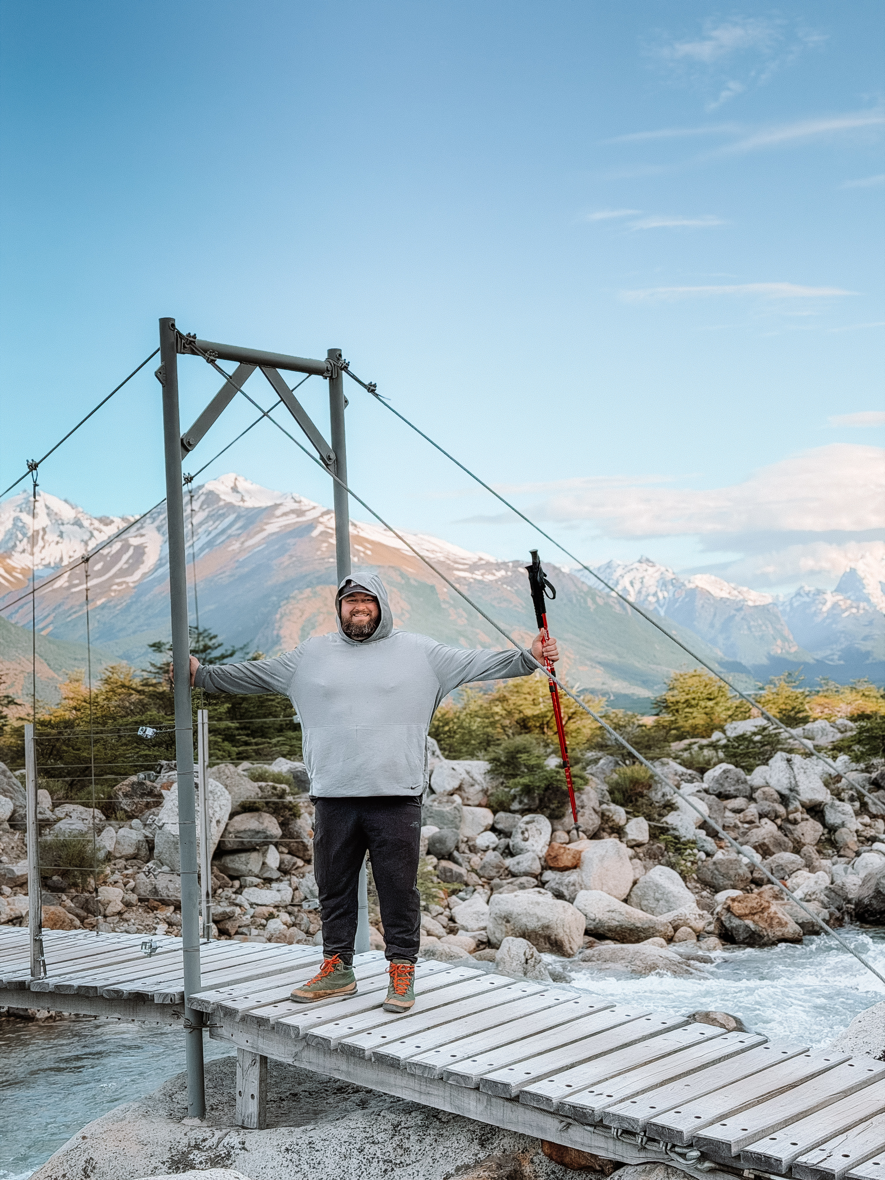 Crossing a footbridge in front of snowcapped peaks in Patagonia