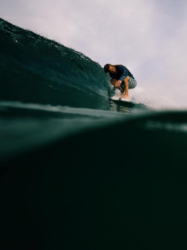 Surfer tucked into a wave, shot from the water