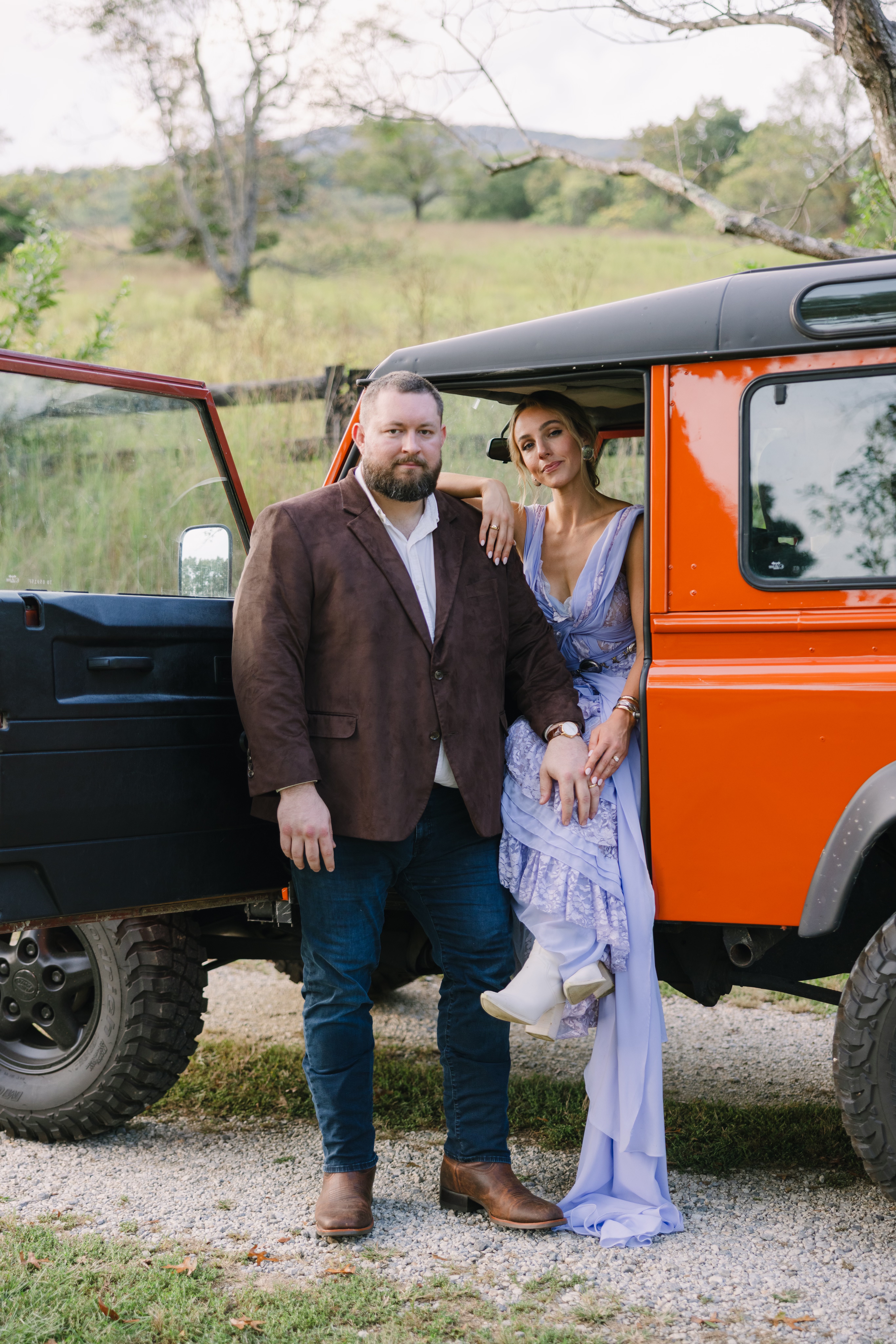 Garrett and Lillie on their wedding day beside an orange Land Rover Defender